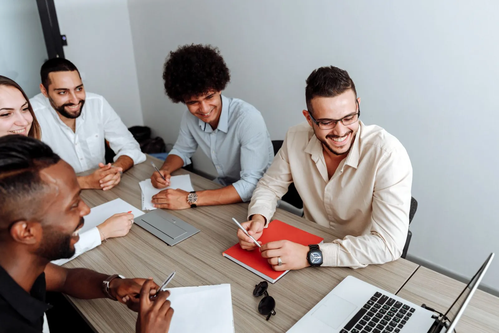 Time reunido em volta da mesa, sorrindo durante uma reunião de trabalho